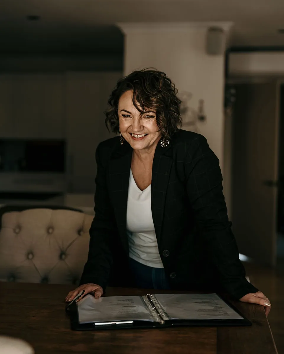 Lea-Anne, Christchurch wedding celebrant, smiling beside her ceremony folder